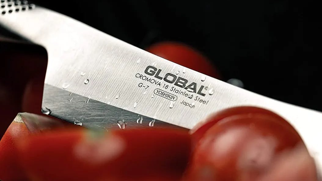 A Global knife slicing a tomato.