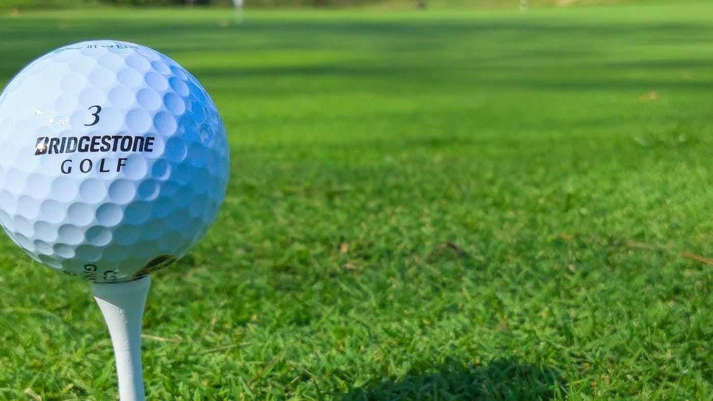 A Bridgestone golf ball sits on a white golf tee.