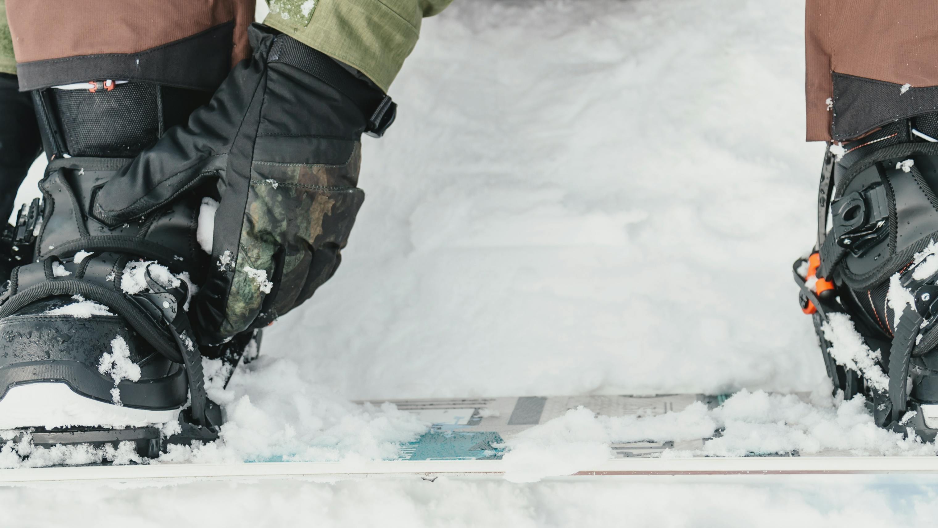 Closeup of a snowboarder buckling his bindings over his boots. 